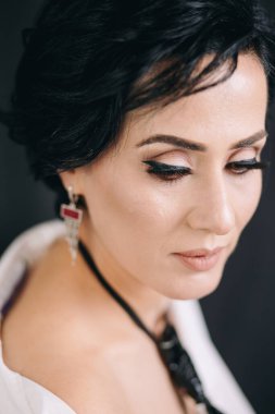 Beyaz gömlekli, düşünceli ve stüdyoda kameraya poz veren düşünceli genç bir kadın.