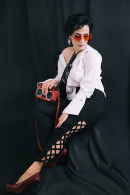 Beyaz gömlekli genç bayanın stüdyoda kameraya poz verirken tüm vücudunu gösteren bir fotoğraf.