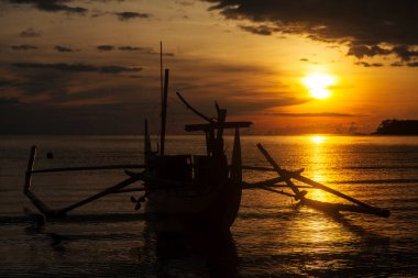 Gün batımında bir balıkçı teknesinin silueti.