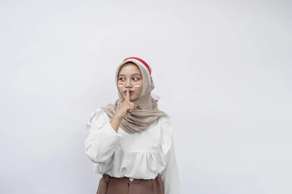 インドネシア独立記念日を祝う若いアジアのイスラム教徒の女性は 白い背景に隔離された唇に押された指で 深刻な顔で揺れていることを伝えます 8月17日のインドネシア独立記念日 — ストック写真