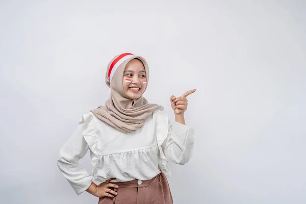 ハッピーな若いアジアのイスラム教徒の女性は 白い背景に隔離されたコピースペースで指を指差します 8月17日のインドネシア独立記念日 — ストック写真
