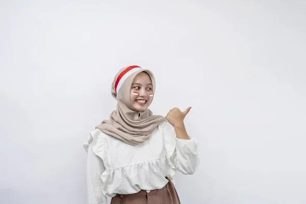 快乐的年轻的亚洲穆斯林女人把手指放在一边 看着被白色背景隔开的复制空间 印度尼西亚独立日 8月17日 — 图库照片