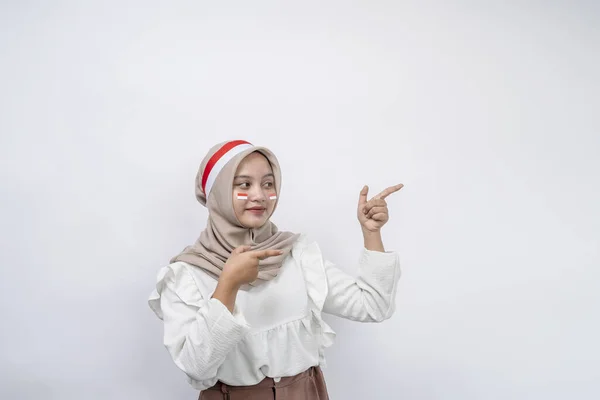 ハッピーな若いアジアのイスラム教徒の女性は 白い背景に隔離されたコピースペースで指を指差します 8月17日のインドネシア独立記念日 — ストック写真