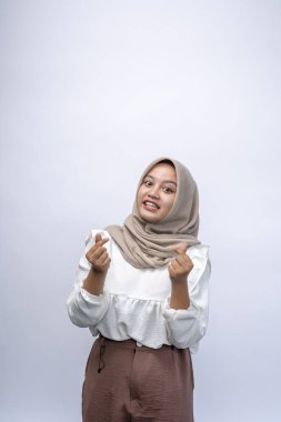 Güzel, güler yüzlü, Endonezyalı, tesettürlü, tesettürlü Müslüman kadın beyaz arka planda izole edilmiş Kore aşk işareti gösteriyor. İnsanlar dini yaşam tarzı konsepti