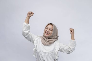Heyecanlı güzel Endonezyalı Müslüman kadın başarıyı kutluyor ve beyaz arka planda izole edilmiş kameraya bakıyor. İnsanlar dini yaşam tarzı konsepti