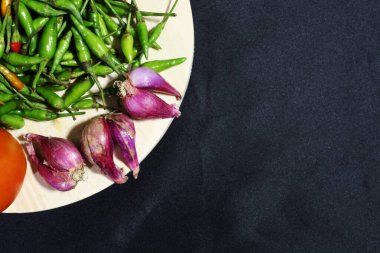 Kırmızı soğan ve siyah arkaplanlı yeşil biber.