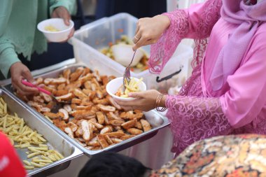Pembe gömlekli kadınlar patates kızartmasını kaseye koyar.