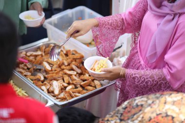 Pembe gömlekli kadınlar patates kızartmasını kaseye koyar.