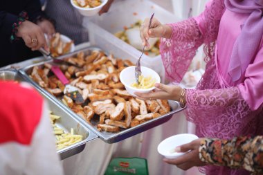 Pembe gömlekli kadınlar patates kızartmasını kaseye koyar.