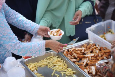 Kadınlar patates kızartmasını kaseye koyar.