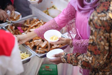 Pembe gömlekli kadınlar patates kızartmasını kaseye koyar.