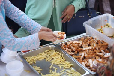 Uzun elbiseli bir kadın kızarmış tavuğu kaseye koydu.