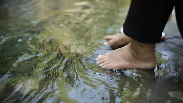 woman\'s feet touch water
