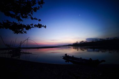 Gölde öğleden sonra atmosferi. Tekne silueti ve manuel balık bulucusuyla.
