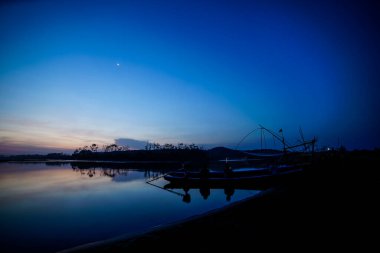 Bir balıkçı teknesinin siluetiyle gün batımının atmosferi.