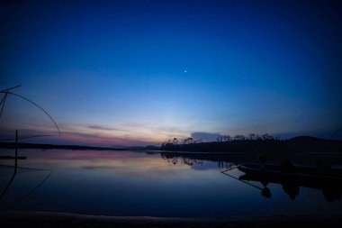 Balıkçı tekneleri ve siluet tepeleriyle gün batımının atmosferi