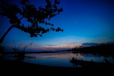 Gün batımının atmosferi balık tutma ekipmanları ve küçük teknelerle dolu.