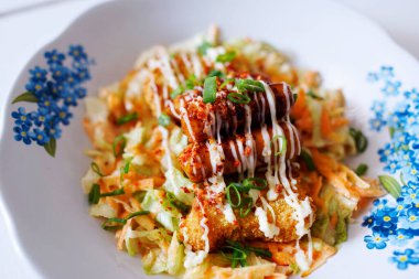 Mayonez soslu tavuk bifteği ve üzerine soğan serpiştirilmiş biftek.