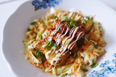 Salata, mayonez soslu tavuk bifteği ve üzerine soğan serpiştirilmiş sığır sosisi.