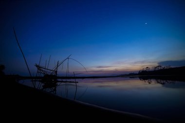 Gün batımının atmosferi balık tutma malzemelerinin siluetiyle
