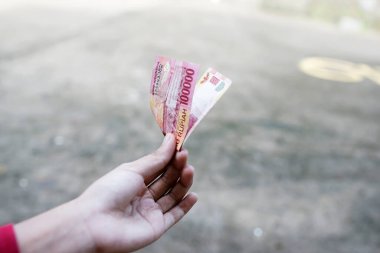 Endonezya rupia parası. Sağ elde 100.000.
