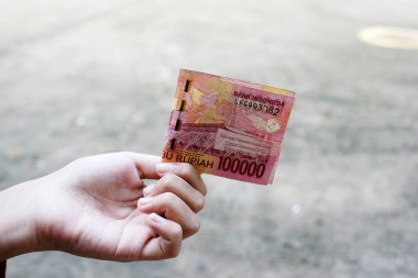 Yüz bin Rupia Endonezya banknotları kadınlar tarafından tutuluyor.