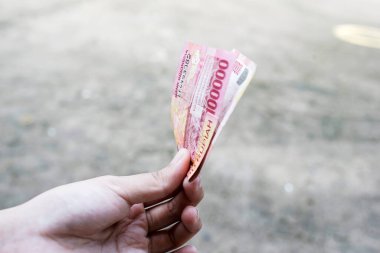 Kadın yüz bin rupiah gösteriyor.