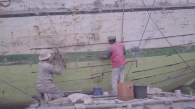SUNDA KELAPA, JAKARTA, İNDONEZYA - 22 Ocak 2017. Hasarlı bir tekneyi tamir eden iki tamircinin faaliyetleri.