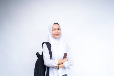 Mutlu Asyalı lise öğrencileri ellerinde kitap ve çanta ile beyaz arka plan, stüdyo çekimi, eğitim konsepti üzerinde izole bir şekilde duruyorlar..