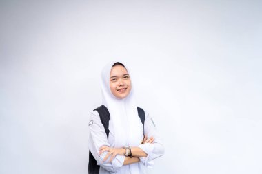 Mutlu Asyalı lise öğrencileri ellerinde kitap ve çanta ile beyaz arka plan, stüdyo çekimi, eğitim konsepti üzerinde izole bir şekilde duruyorlar..