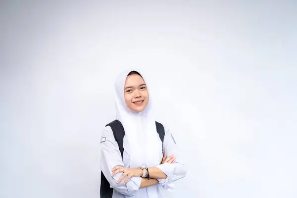 Mutlu Asyalı lise öğrencileri ellerinde kitap ve çanta ile beyaz arka plan, stüdyo çekimi, eğitim konsepti üzerinde izole bir şekilde duruyorlar..