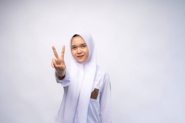 Heyecanlı Endonezyalı beyaz ve gri üniformalı lise öğrencisi iki numarayı el hareketleriyle gösteriyor.