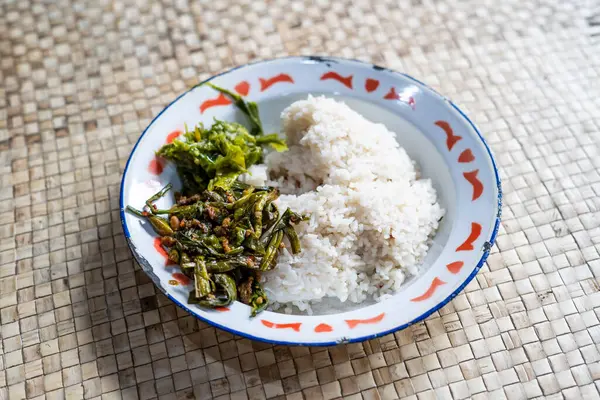 stock image Tumis Genjer. Sauteed yellow velvet leaves with fermented soybeans. Served in one serving of rice which is plated with green chili