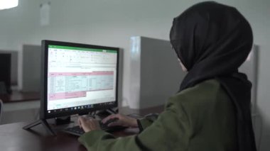 Öğrenciler bilgisayar laboratuvarında tesettürlü bilgisayarlar üzerinde çalışıyorlar. Müslüman öğrenciler