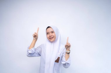 Beyaz arka planda üniforması olan Asyalı kız öğrenciyi işaret ederek mutlu oldun.