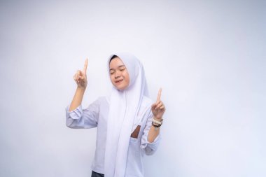 Beyaz arka planda üniforması olan Asyalı kız öğrenciyi işaret ederek mutlu oldun.