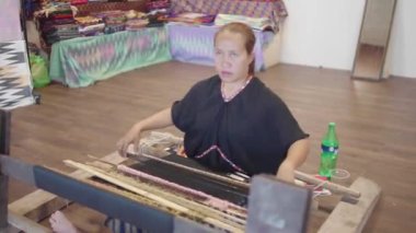 LOMBOK, İNDONEZYA - 26 Ekim 2019: Geleneksel lombok kumaşı, Tenun ya da Weaving ören Endonezyalı bir kadın, ipliğin uzunluk ve çapraz birleşimiyle üretilen kumaş üretiminde kullanılan bir tekniktir..