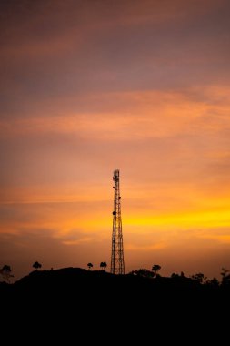 Telekomünikasyon kulesinin silueti Anten, gün batımında tepede