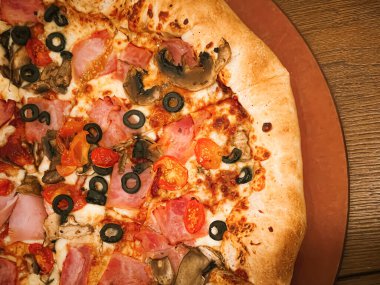 Pizza capriciosa with cheese stuffed crust in pizzeria, food close-up