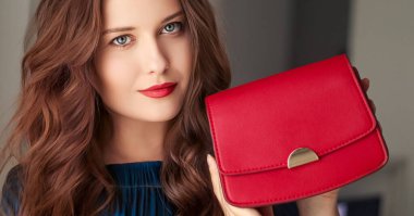 Moda ve aksesuarlar, küçük kırmızı bir çanta taşıyan mutlu güzel bir kadın içinde altın detaylar olan şık bir aksesuar ve lüks alışveriş konsepti olan küçük kırmızı bir çanta.