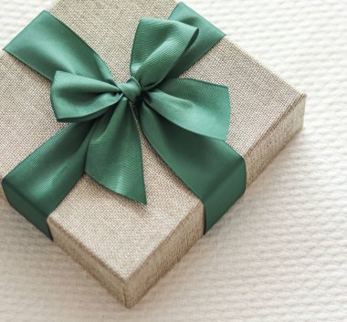 Holiday present and luxury online shopping delivery, wrapped linen gift box with green ribbon on bed in bedroom, chic countryside style, close-up