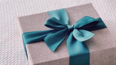 Holiday present and luxury online shopping delivery, wrapped linen gift box with blue ribbon on bed in bedroom, chic countryside style, close-up