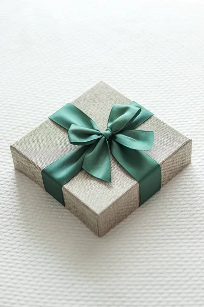 Holiday present and luxury online shopping delivery, wrapped linen gift box with green ribbon on bed in bedroom, chic countryside style, close-up