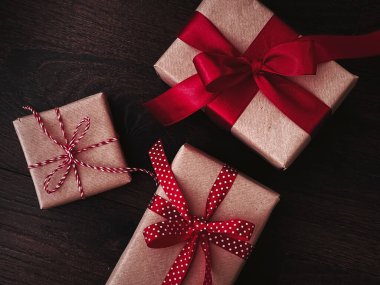 Noel hediyeleri ve geleneksel bayram hediyeleri, ahşap arka planda klasik Noel hediyesi kutuları, kırmızı kurdeleyle sarılmış el işi kağıtları, mevsimsel tatiller için klasik kır tarzı.