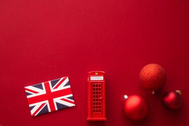 İngiltere 'de Noel tatili geleneği ve mutlu tatiller düzlük, İngiliz bayrağı, Londra telefon kulübesi ve flatlay tasarımı olarak şenlikli kırmızı arka plan üzerine xmas süslemesi, üst görünüm