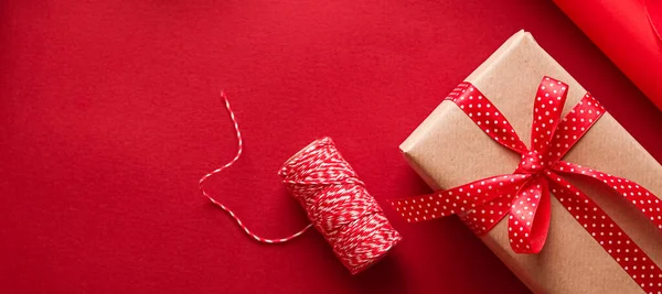 クリスマスの準備 ボクシングの日と休日の贈り物 包装用具や装飾品として赤い背景のギフトボックスのためのクリスマスクラフト紙とリボン 休日のフラットレイデザインとしてのDiyプレゼント — ストック写真
