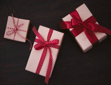Noel hediyeleri ve geleneksel bayram hediyeleri, ahşap arka planda klasik Noel hediyesi kutuları, kırmızı kurdeleyle sarılmış el işi kağıtları, mevsimsel tatiller için klasik kır tarzı.
