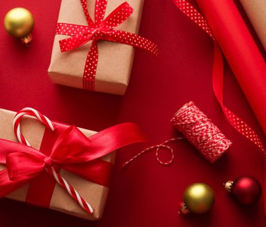 Noel hazırlığı, boks günü ve bayram hediyeleri, Noel hediyesi kağıtları ve kırmızı arka plandaki hediye kutuları için kurdeleler paketleme araçları ve dekorasyonlar olarak sunuluyor.