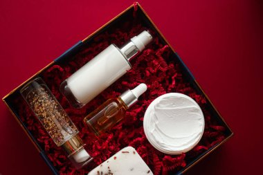 Güzellik kutusu abonelik paketi ve lüks cilt bakım ürünleri, spa ve kozmetik ürünleri kırmızı arka planda yatıyordu, sağlık kozmetiği tatil hediyesi olarak, çevrimiçi alışveriş dağıtımı, düz görünüm