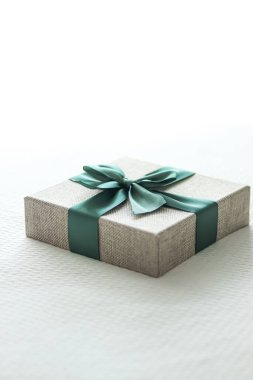 Holiday present and luxury online shopping delivery, wrapped linen gift box with green ribbon on bed in bedroom, chic countryside style, close-up